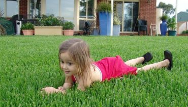 girl-lying-on-grass-in-front-of-their-house