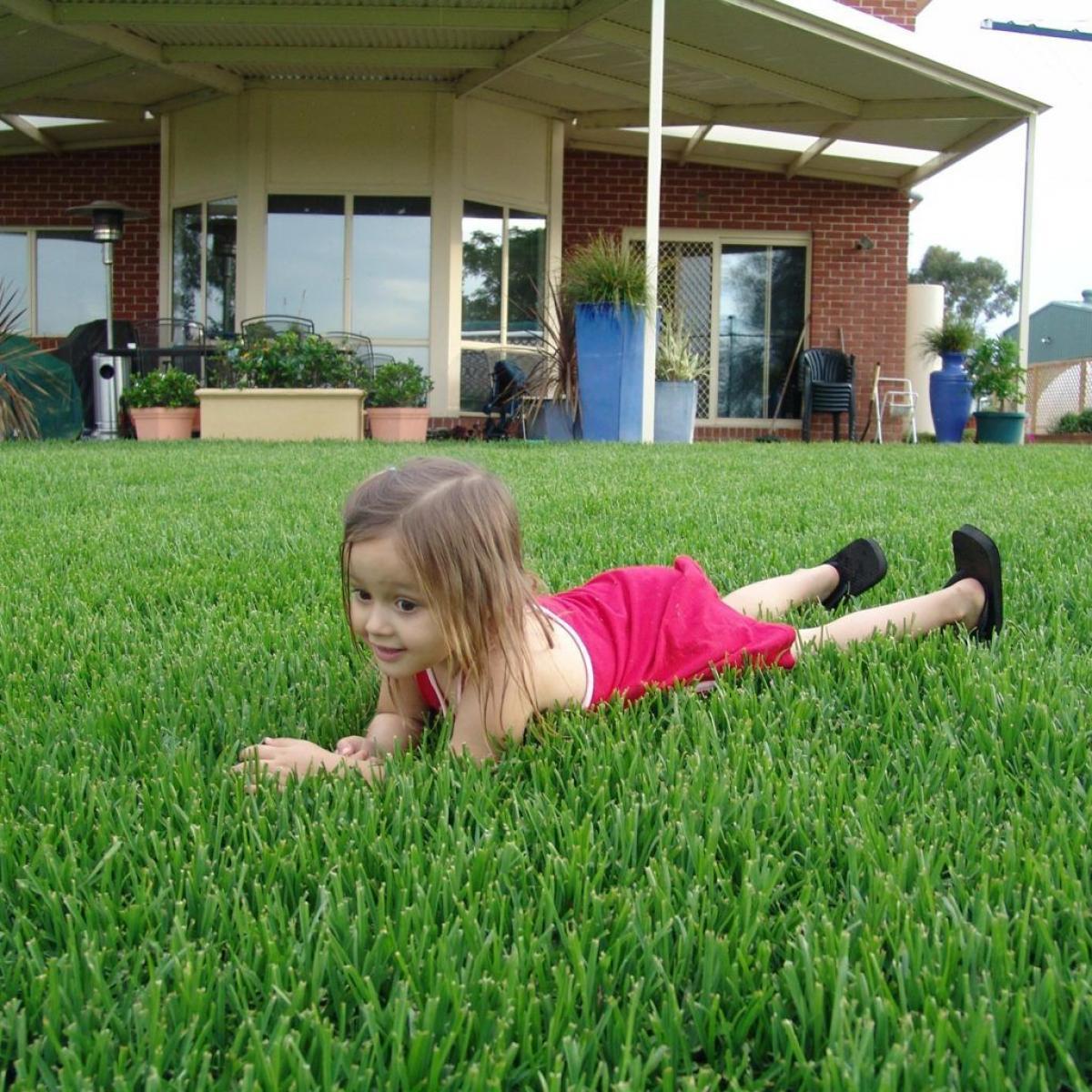 girl-lying-on-grass-in-front-of-their-house